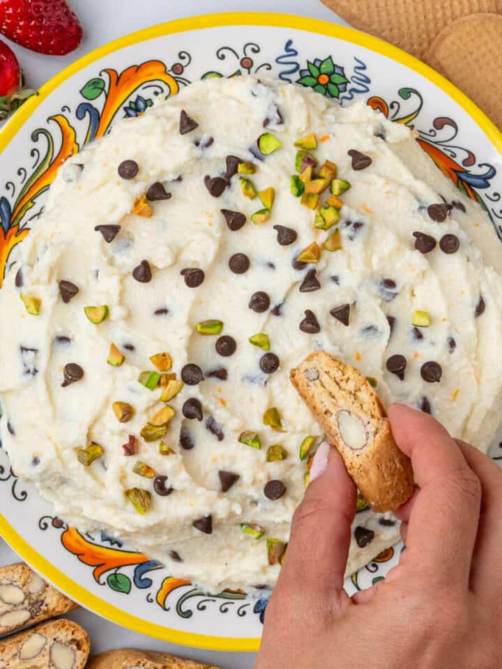 Biscotti being dipped into cannoli dip