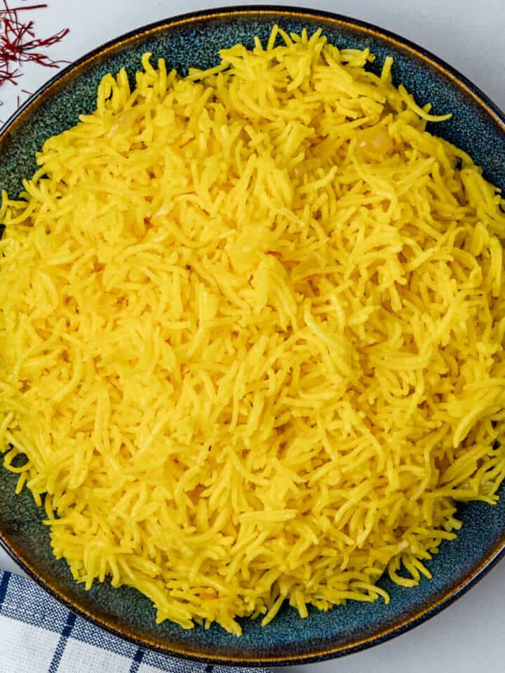 Saffron rice served in a bowl with saffron threads on the side