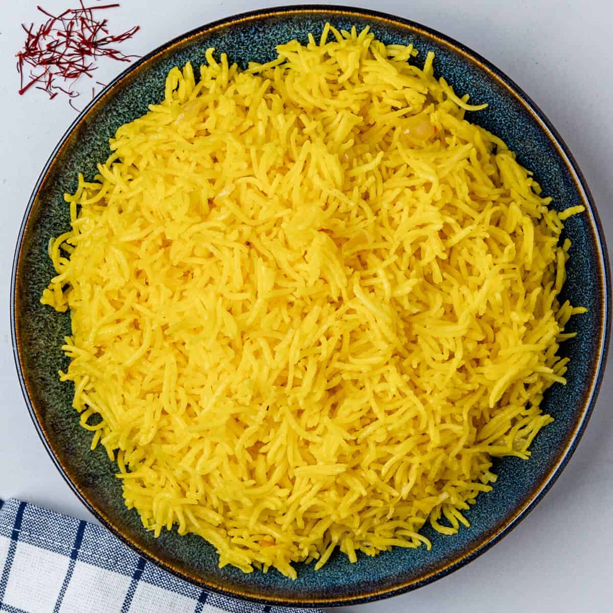 Saffron rice served in a bowl with saffron threads on the side