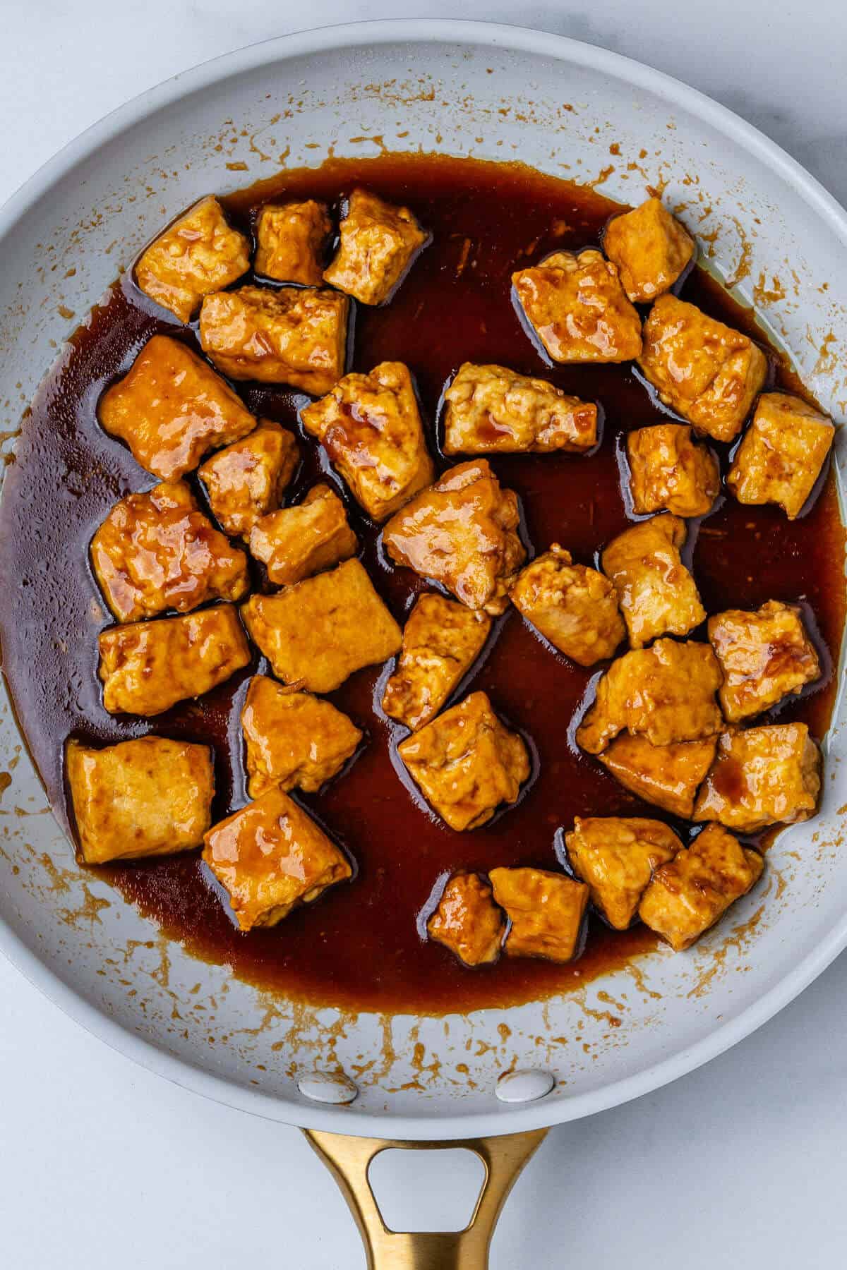 Cooked tofu in a pan covered in teriyaki sauce