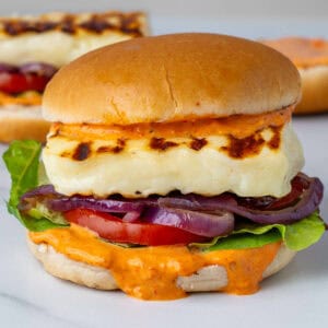 Halloumi burger with grilled onions, spicy red pepper sauce and veggies