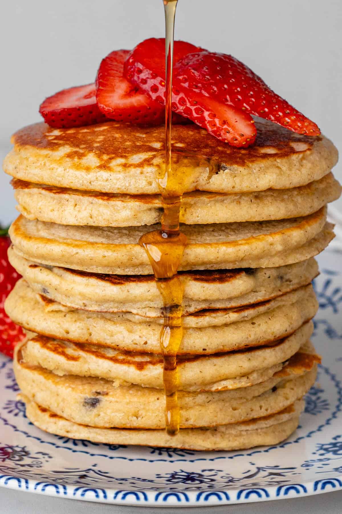 Maple syrup being poured on a stack of Oat Flour Pancakes