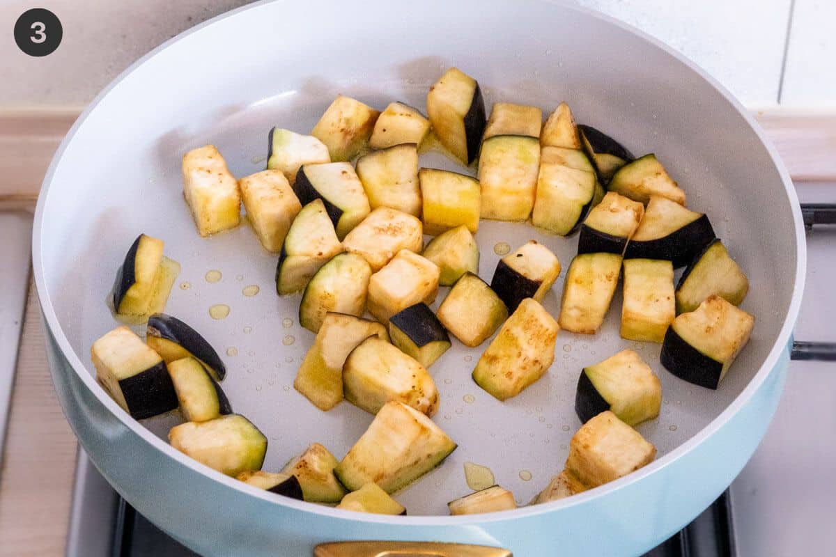 Eggplant cubes being fried in a pan with oil