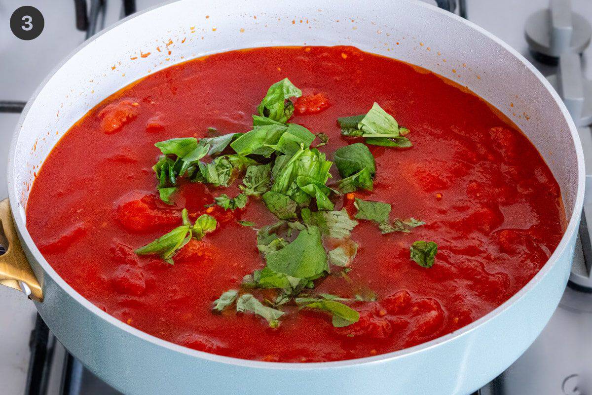 Fresh basil added to a pan of tomato sauce