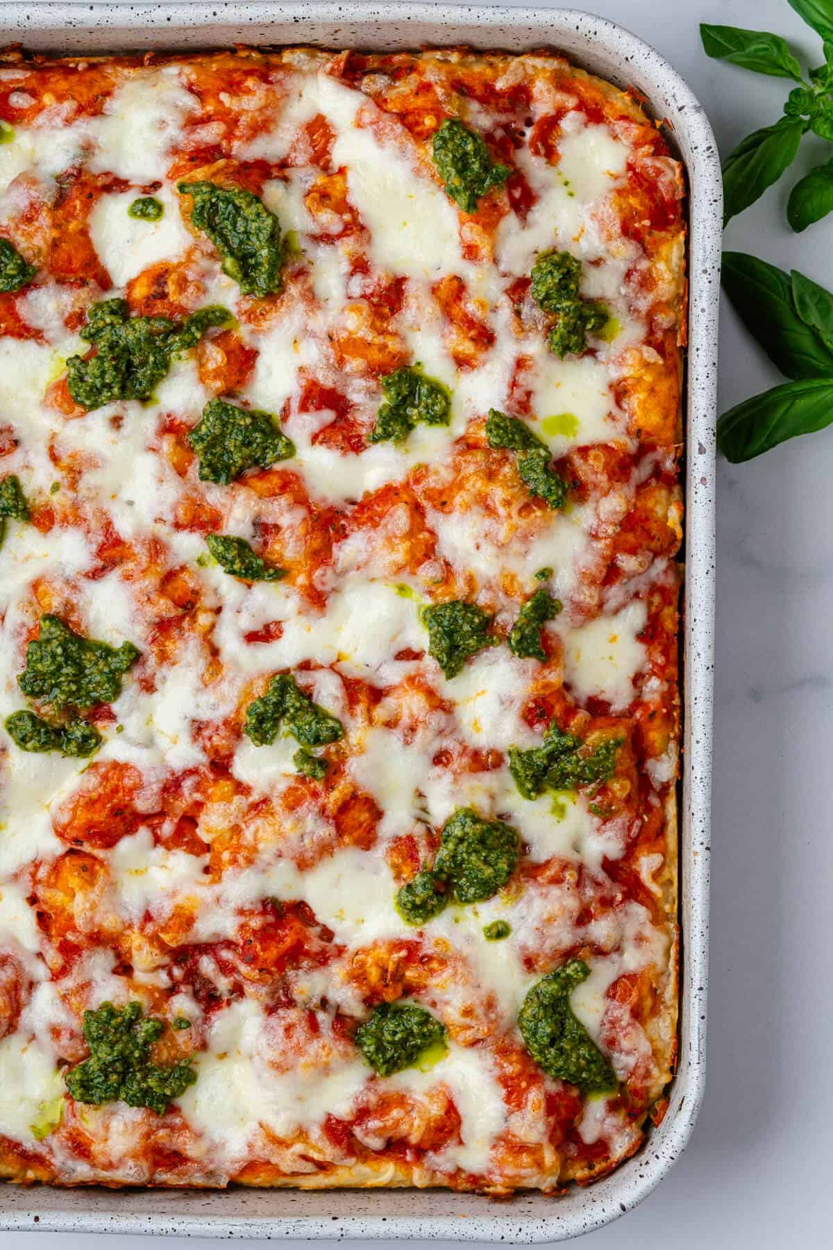 Oven tray of focaccia pizza topped with basil pesto