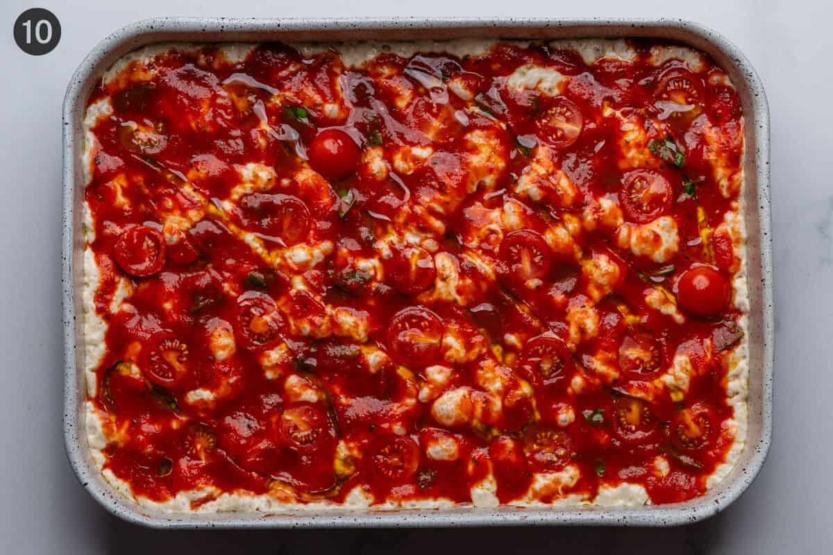 Tomato sauce and toppings placed on dough before being baked