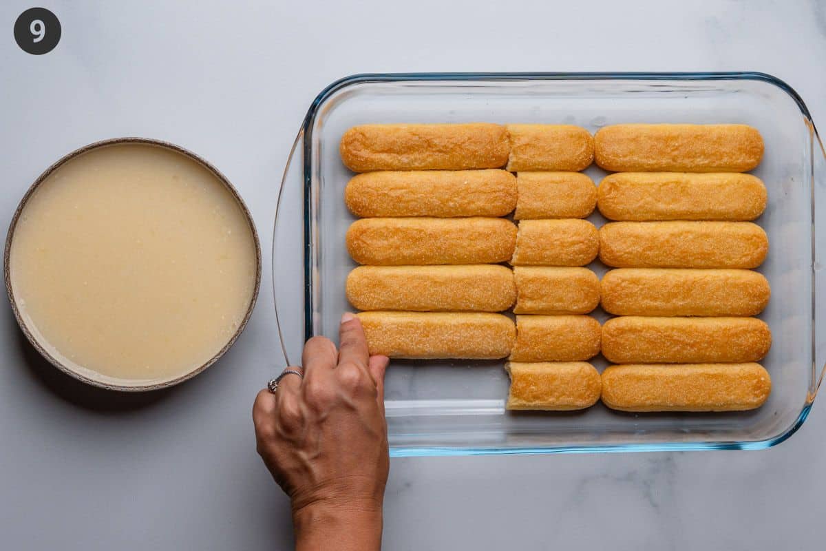 Soaked ladyfinger biscuits being placed into tray