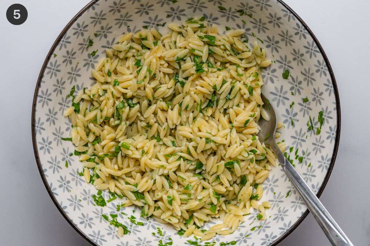 Orzo pasta mixed with dressing and fresh parsley