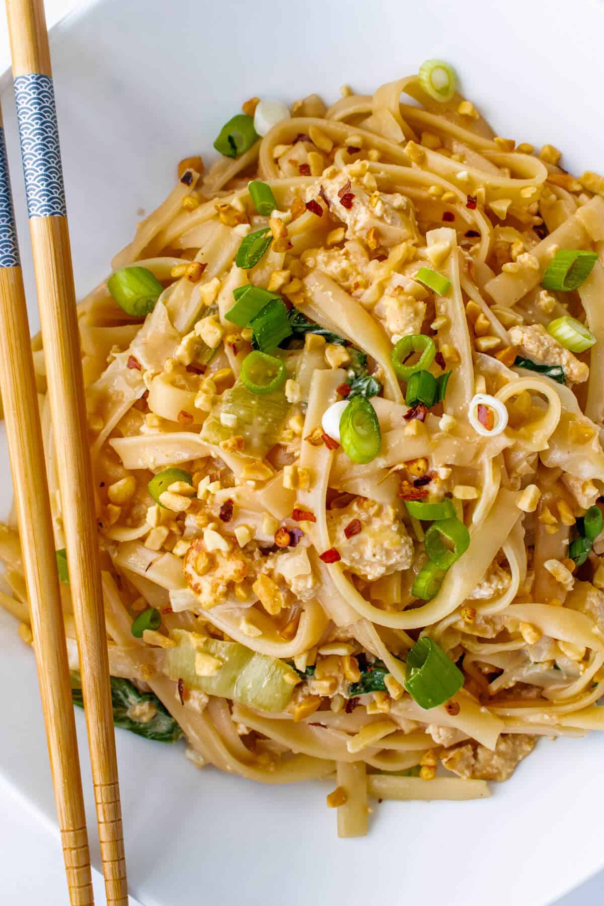 Peanut noodles in a bowl with chop sticks
