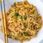 Peanut noodles with green onions, crushed peanuts and chopsticks