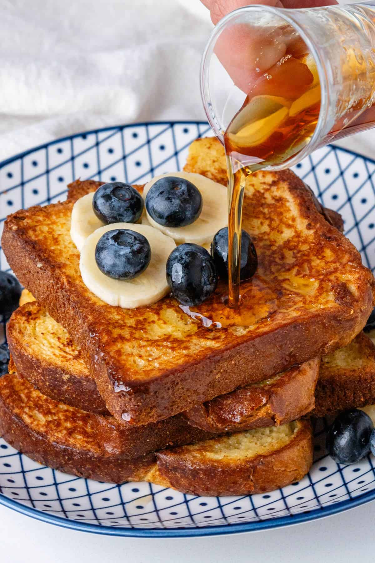 Maple syrup being poured on top of Brioche French Toast