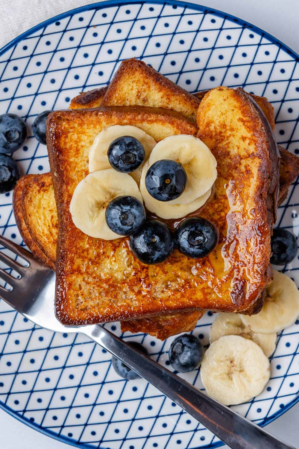 Brioche french toast on a plate with blueberries and banana slices