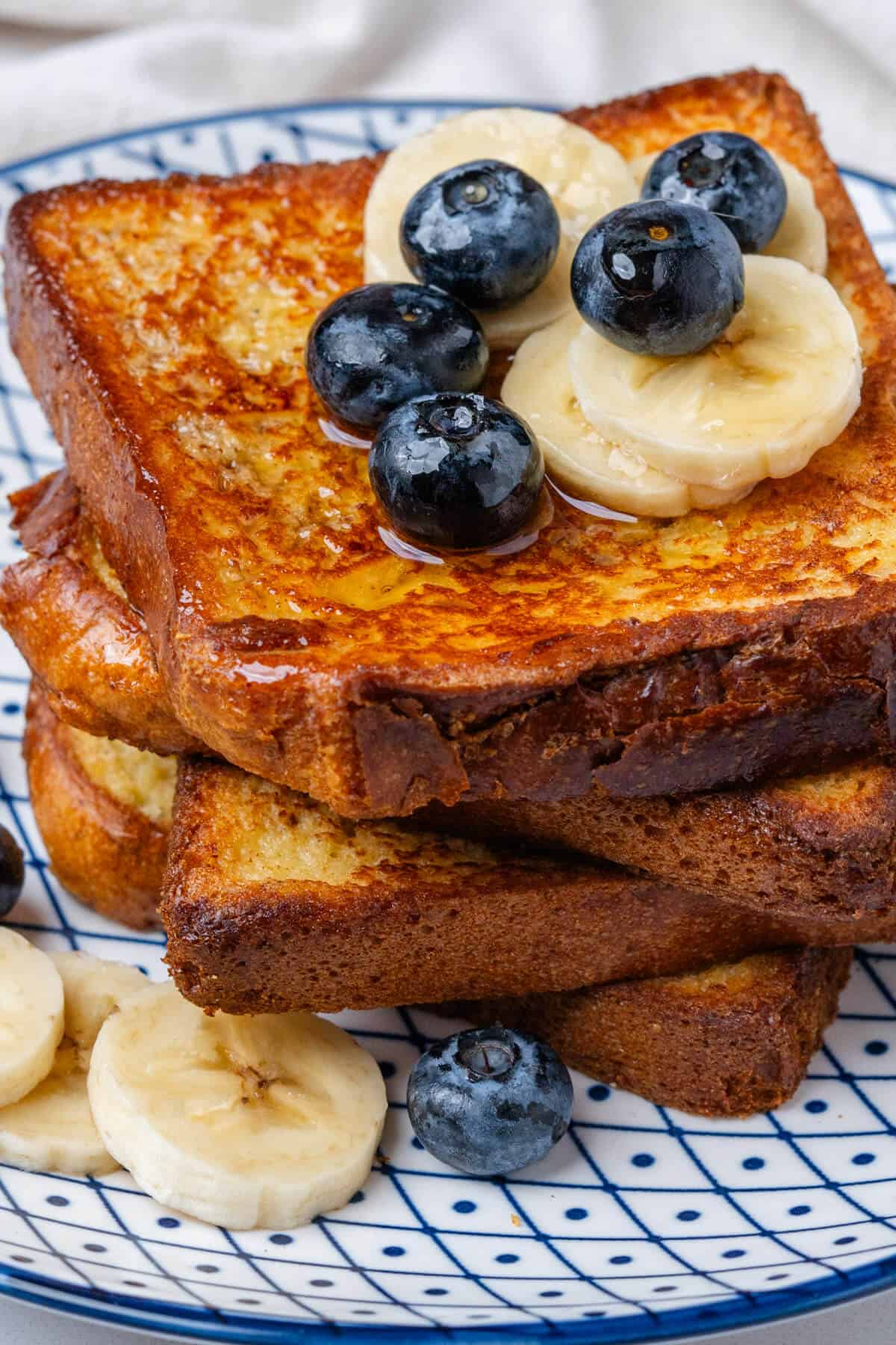 Toast stacked on a plate with blueberries and banana slices