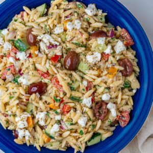 Greek orzo salad in a bowl topped with feta cheese