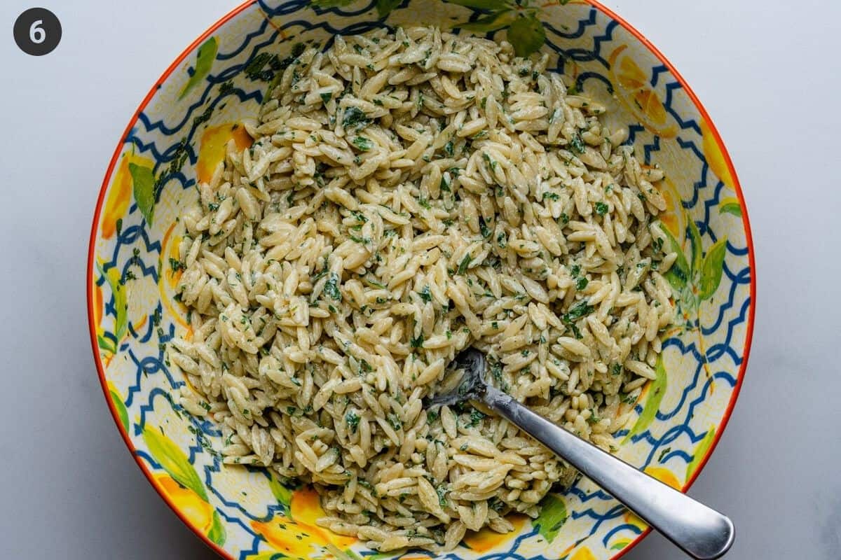 Dressing added to cooked pasta in a large bowl