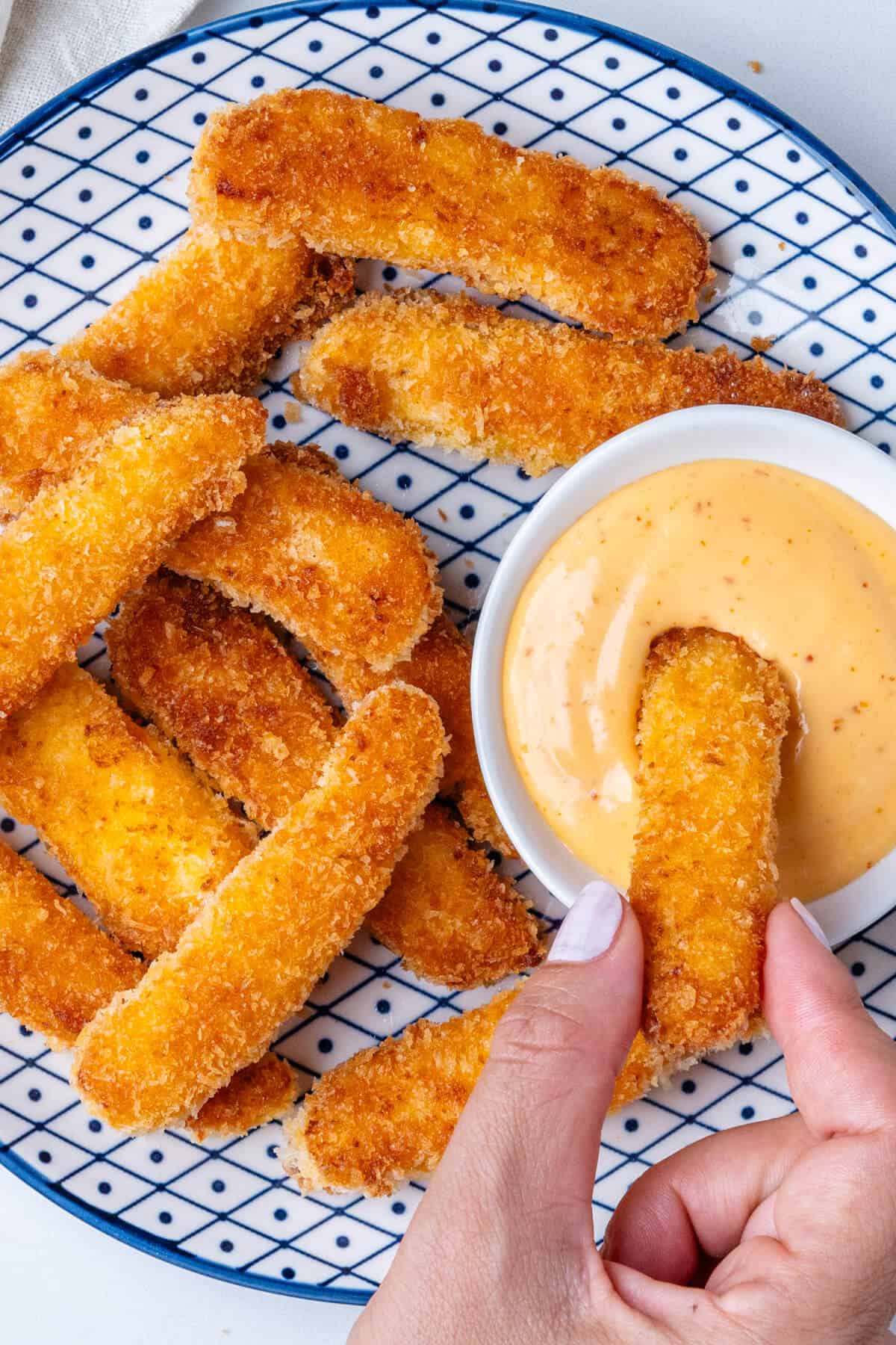 Plate of halloumi fries with one being dipped into aioli