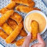 Halloumi fries on a plate being dipped into a sriracha aioli