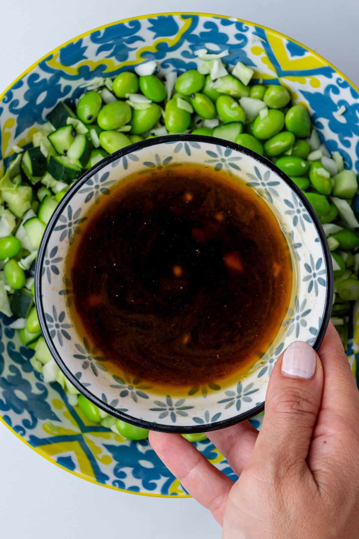 Sesame dressing being poured into a edamame salad