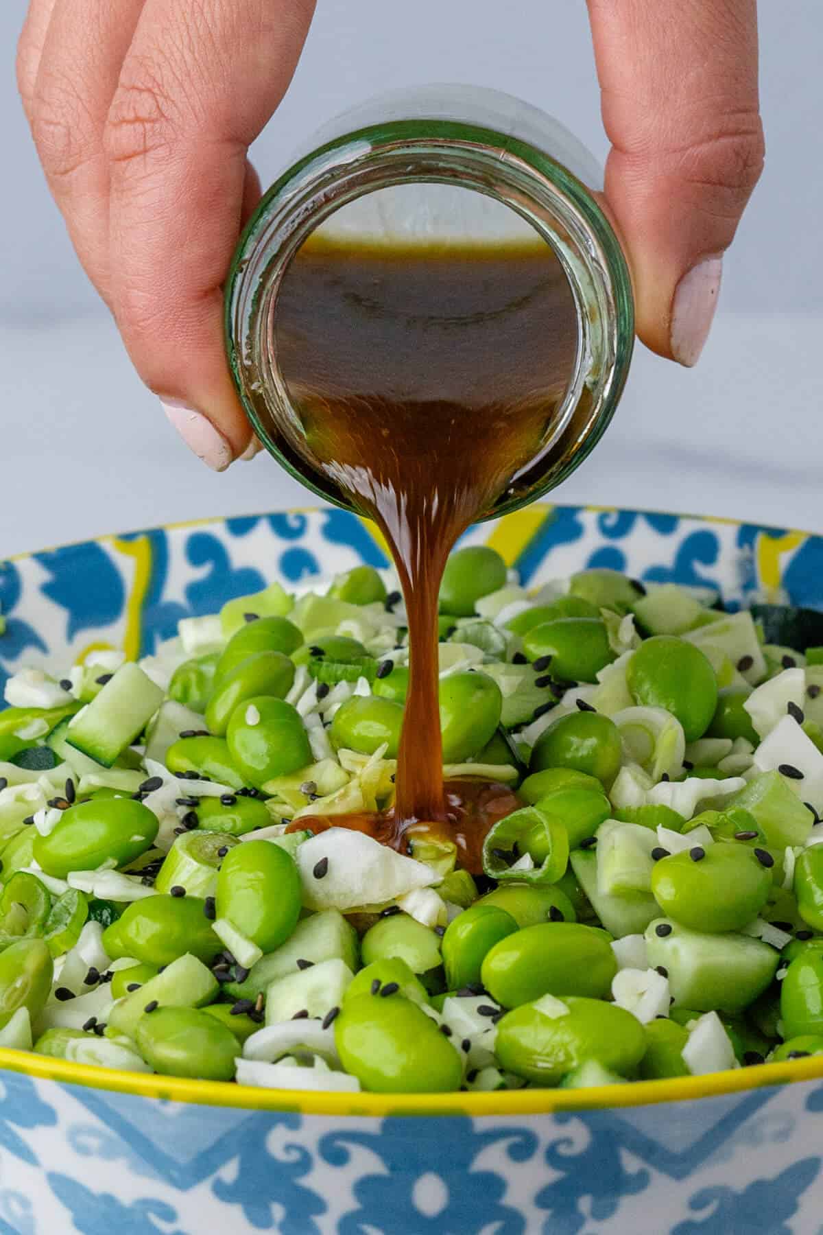 Sesame dressing being poured into salad bowl