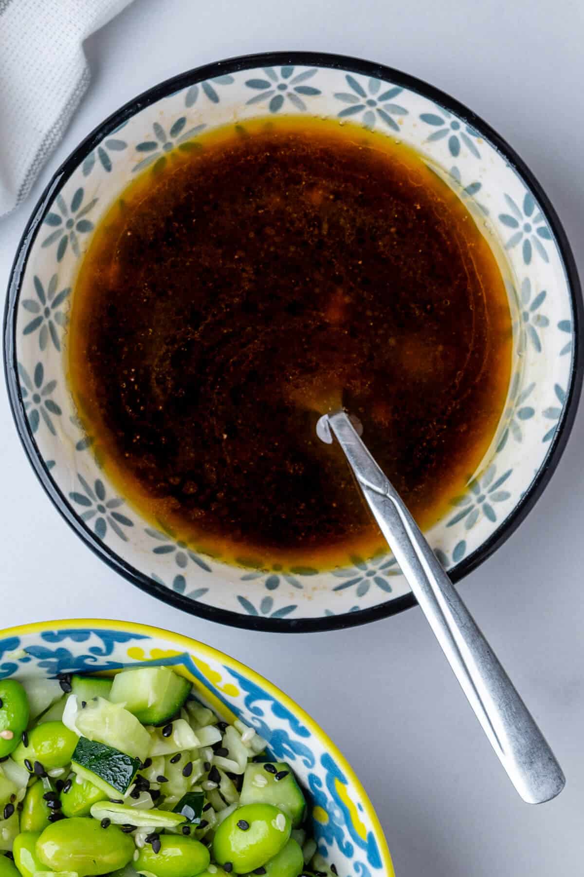 Dressing in a small bowl with salad on the side