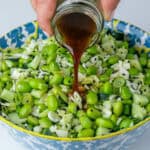 Sesame dressing being poured into edamame salad