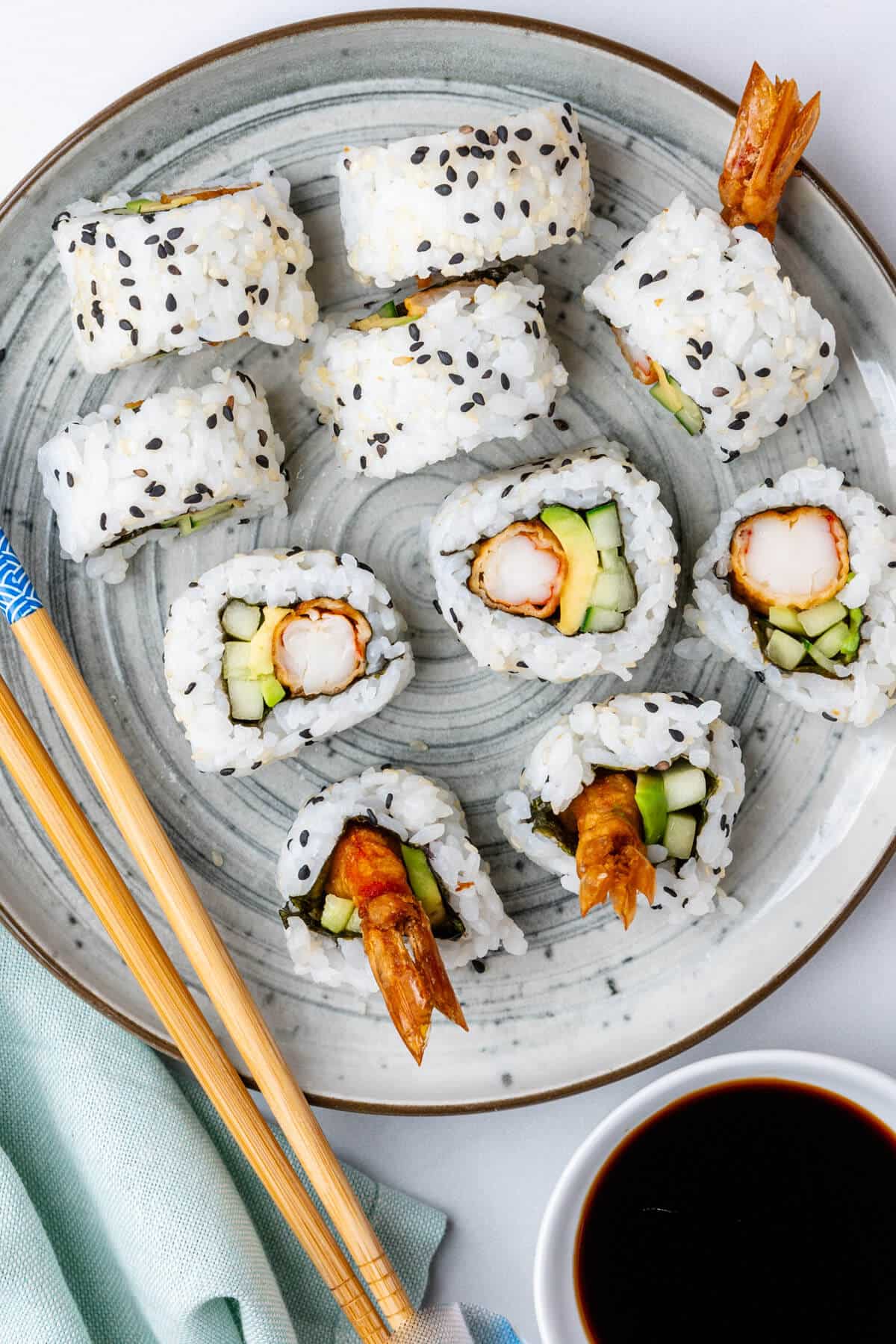 Plate of sushi cut in pieces with chopsticks and soy sauce