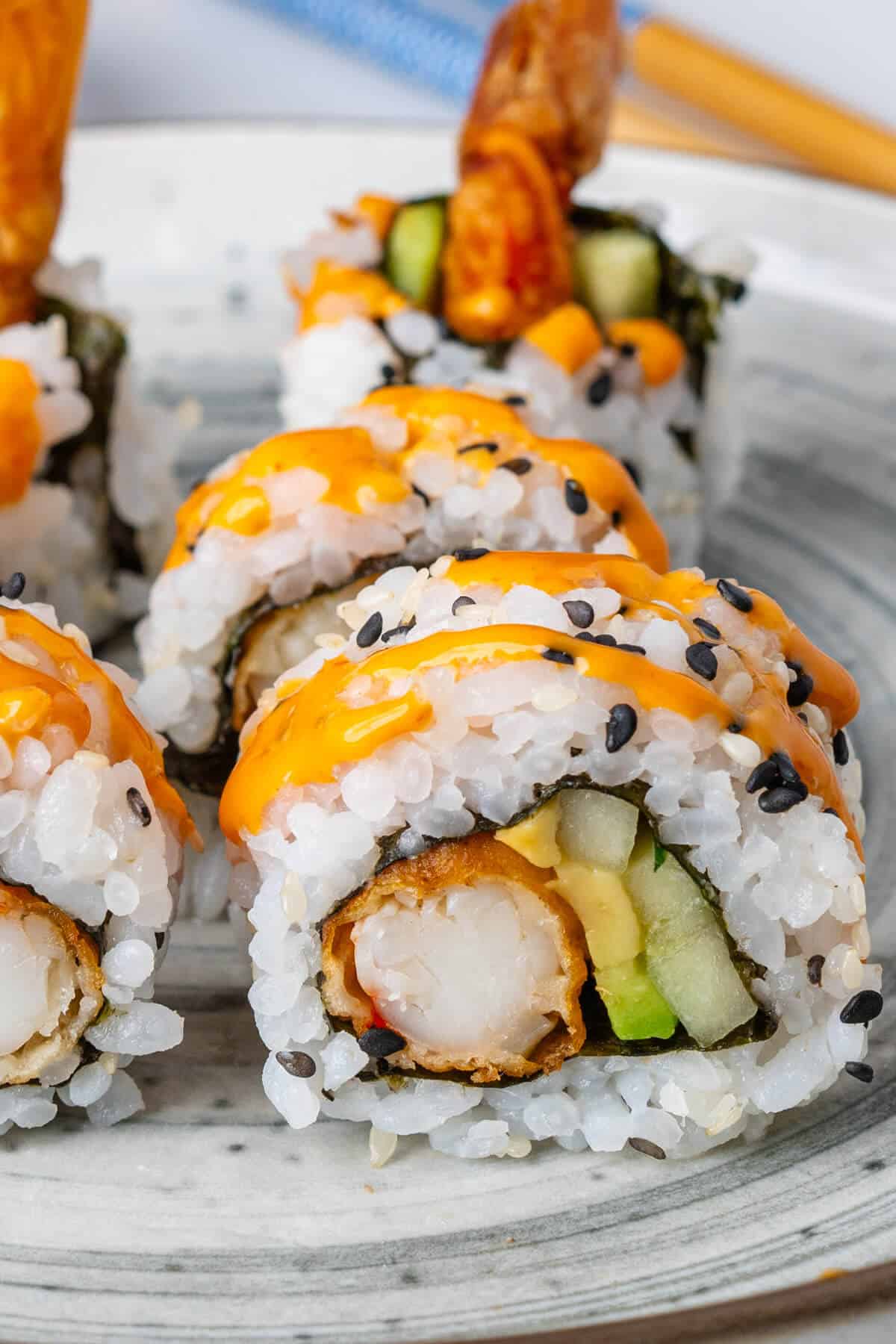 Close up of cut sushi roll with spicy sriracha mayo on top