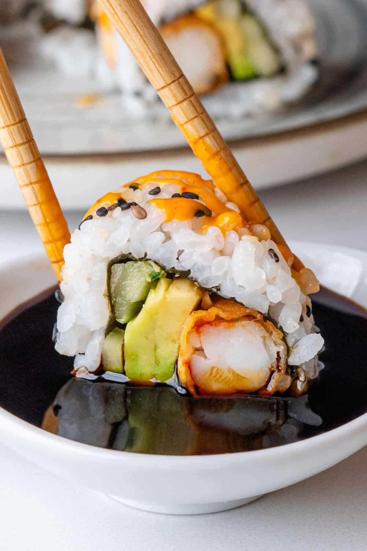 Piece of sushi being dipped into soy sauce