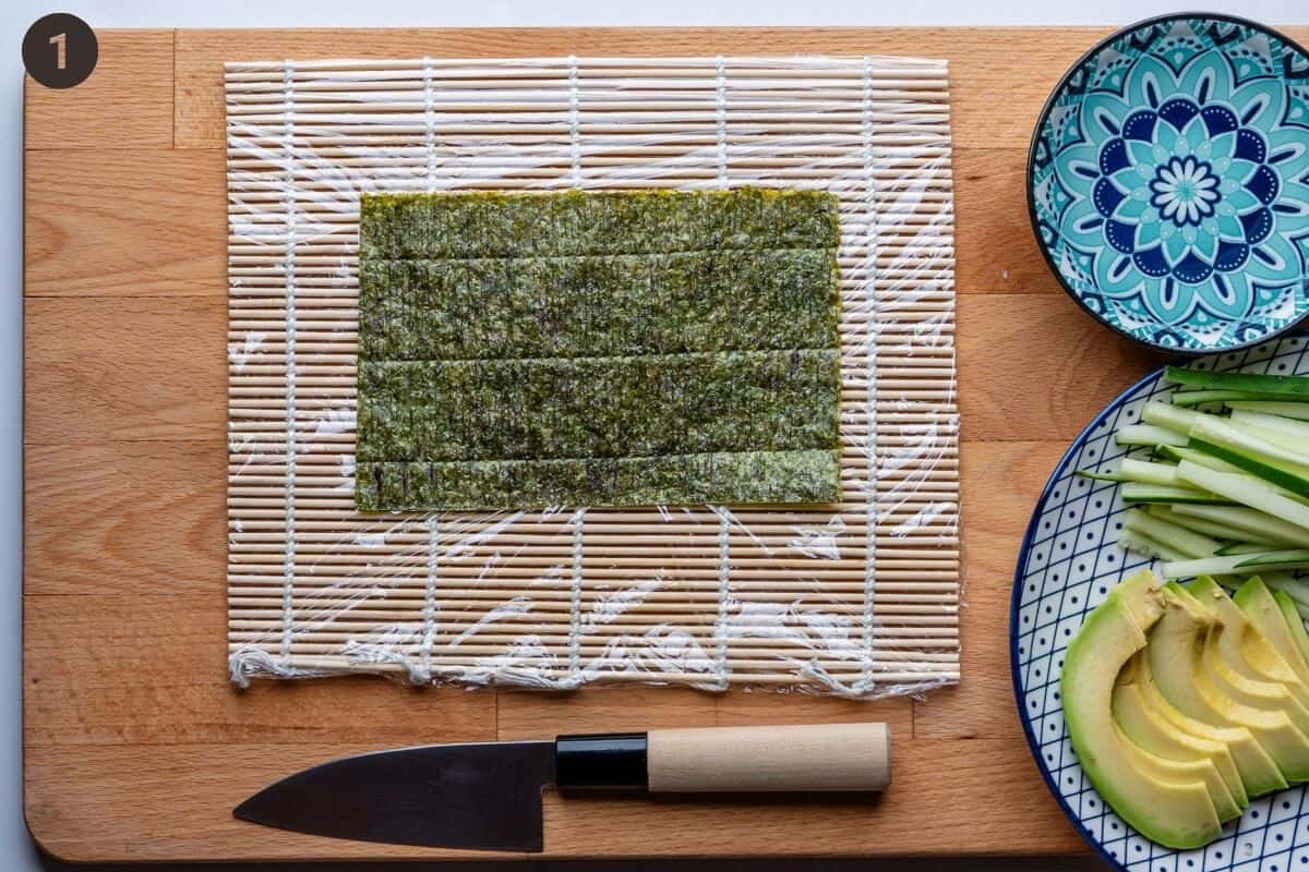 Sushi station with bamboo matt, nori sheet, water bowl and fillings