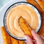 Fry being dipped into a bowl of sriracha aioli