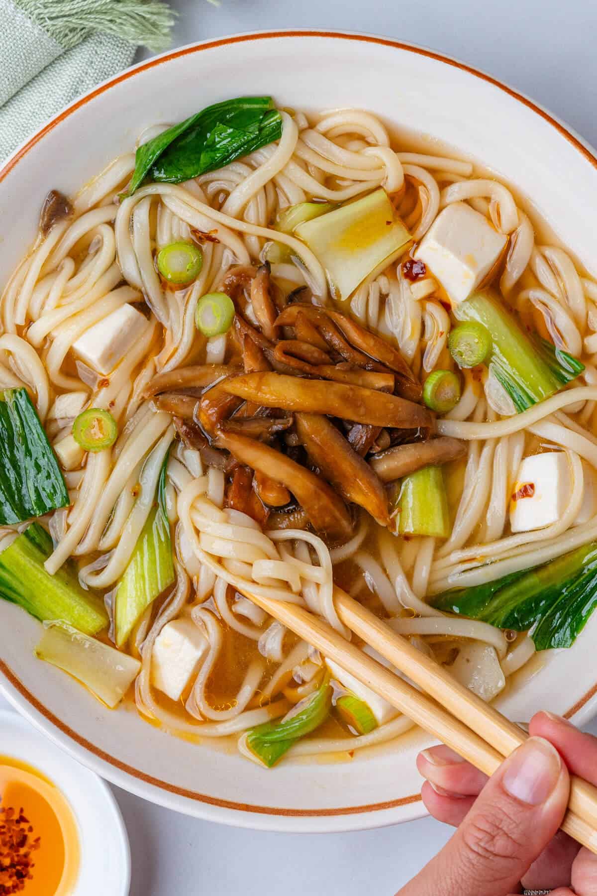 Chopsticks being pulled out of the bowl of miso noodle soup