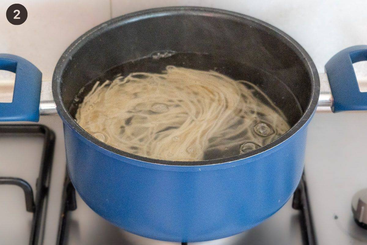 Udon noodles being cooked in boiling water