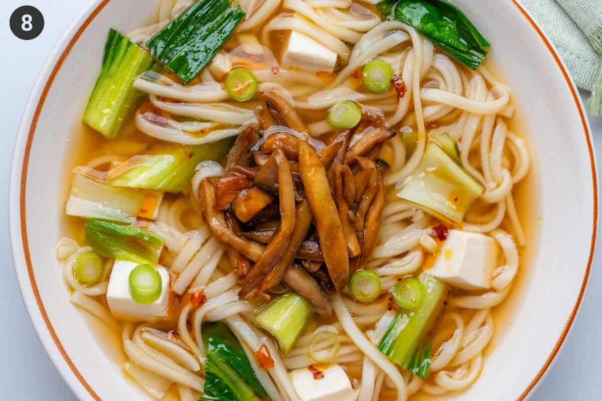 Udon noodle soup topped with mushrooms, spring onions and chili oil