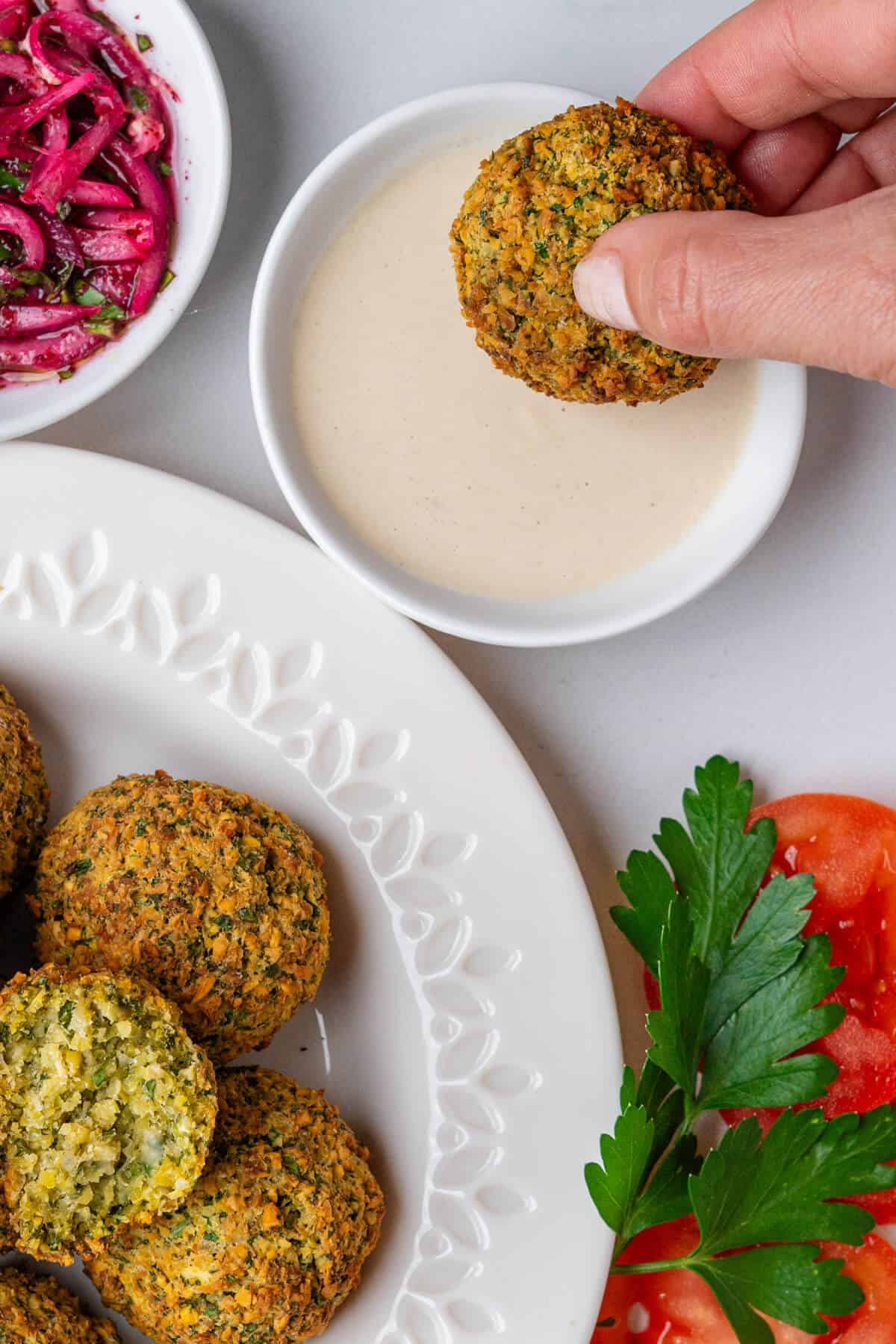 Falafel being dipped into a tahini sauce