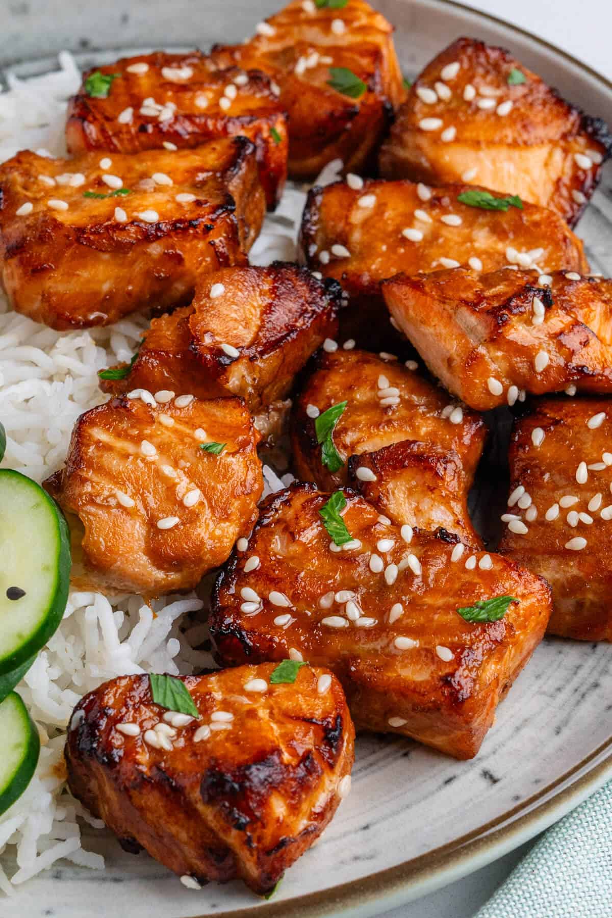 Salmon bites on a plate with rice and cucumbers