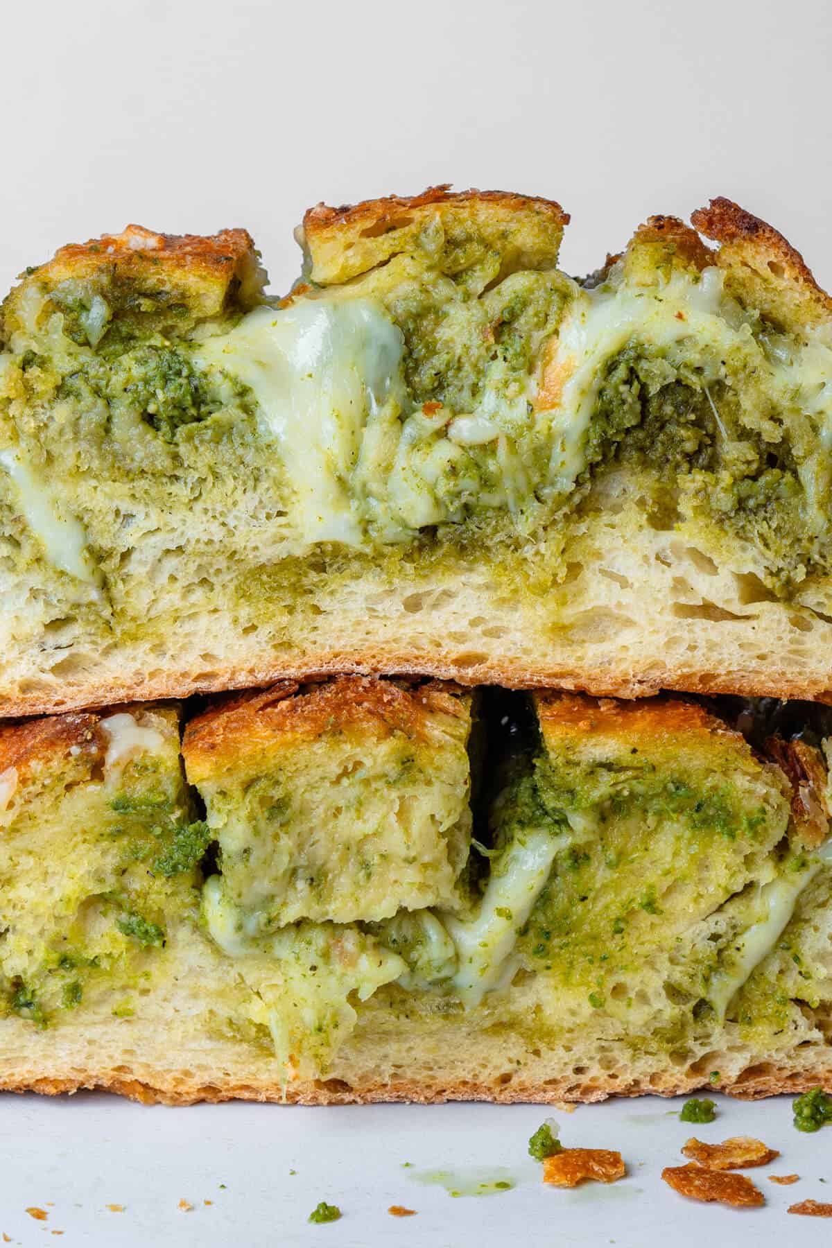 Bread cut in half to show the inside of melted cheese and pesto