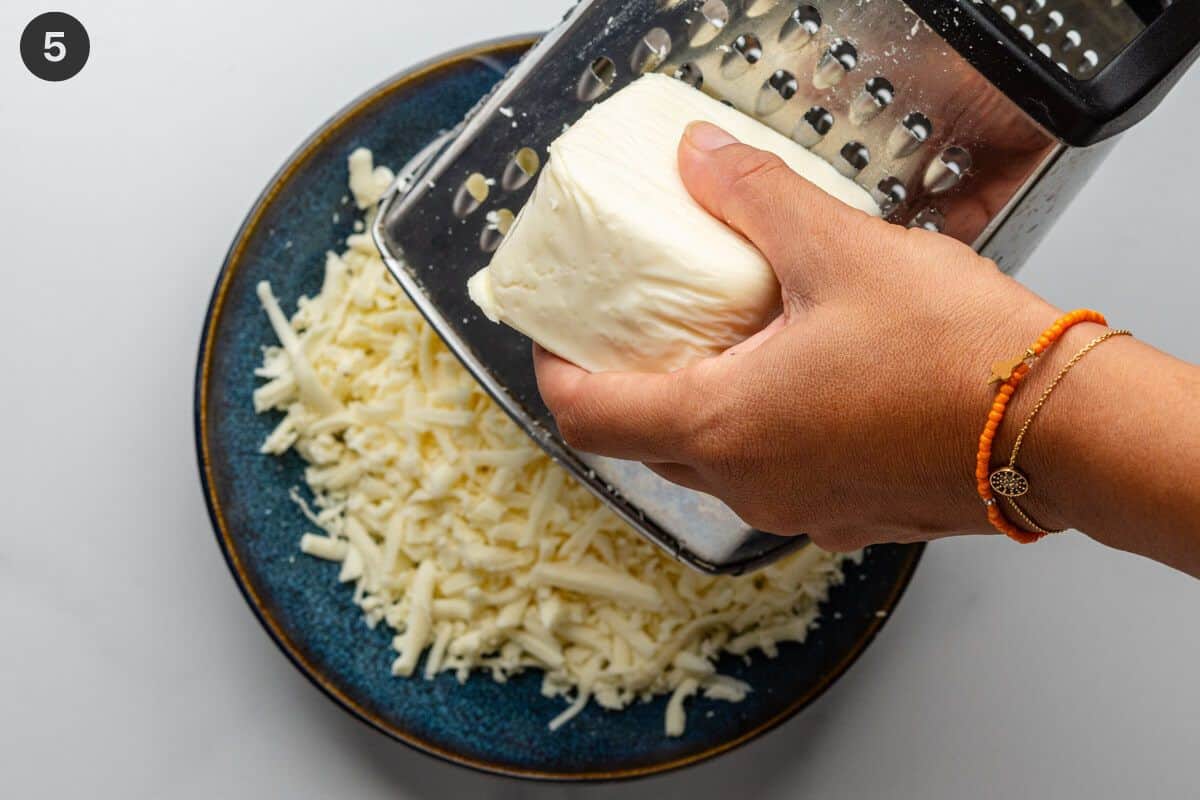 mozzarella being grated into a bowl