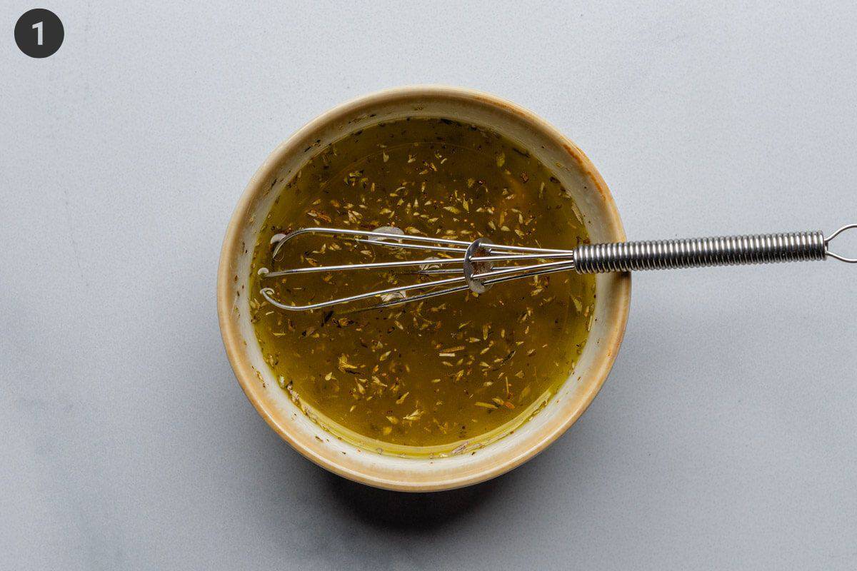 Olive oil dressing in a small bowl with whisk