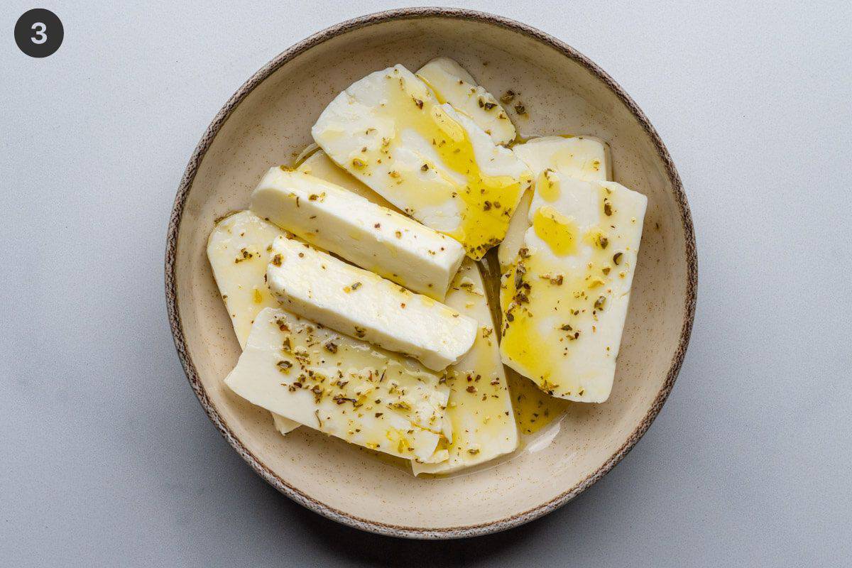 Halloumi pieces in a bowl with olive oil dressing