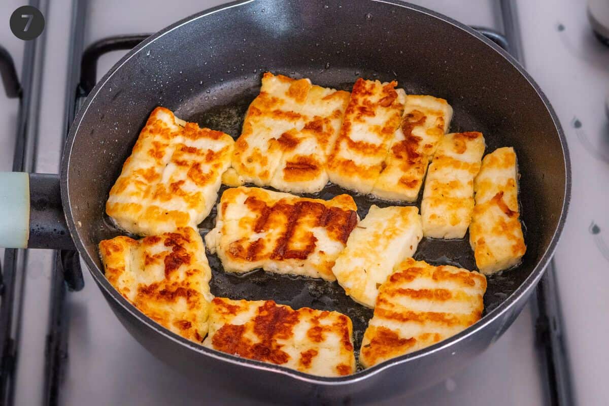 Halloumi pieces flipped on a pan