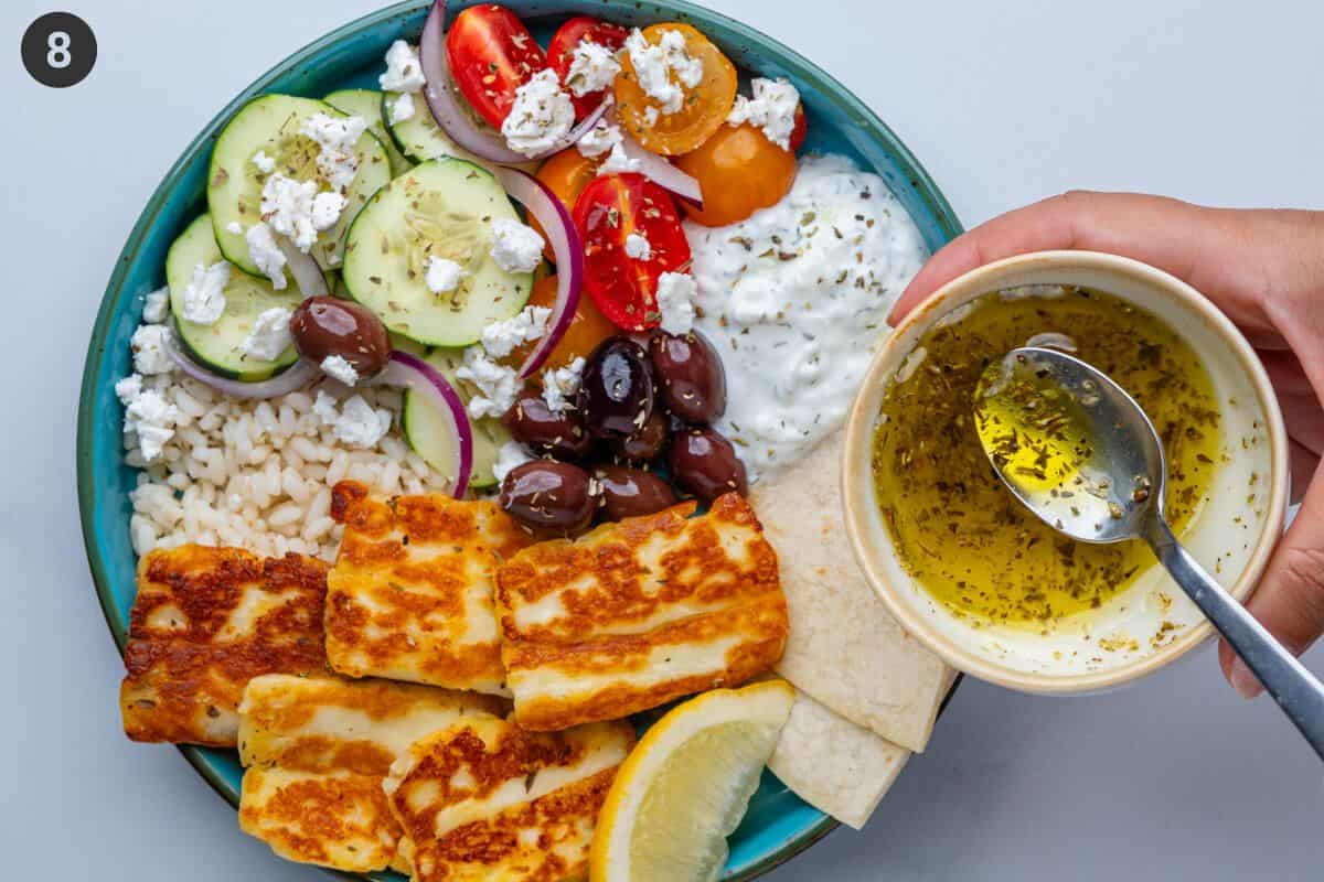 Olive oil dressing about to be poured over a Greek bowl