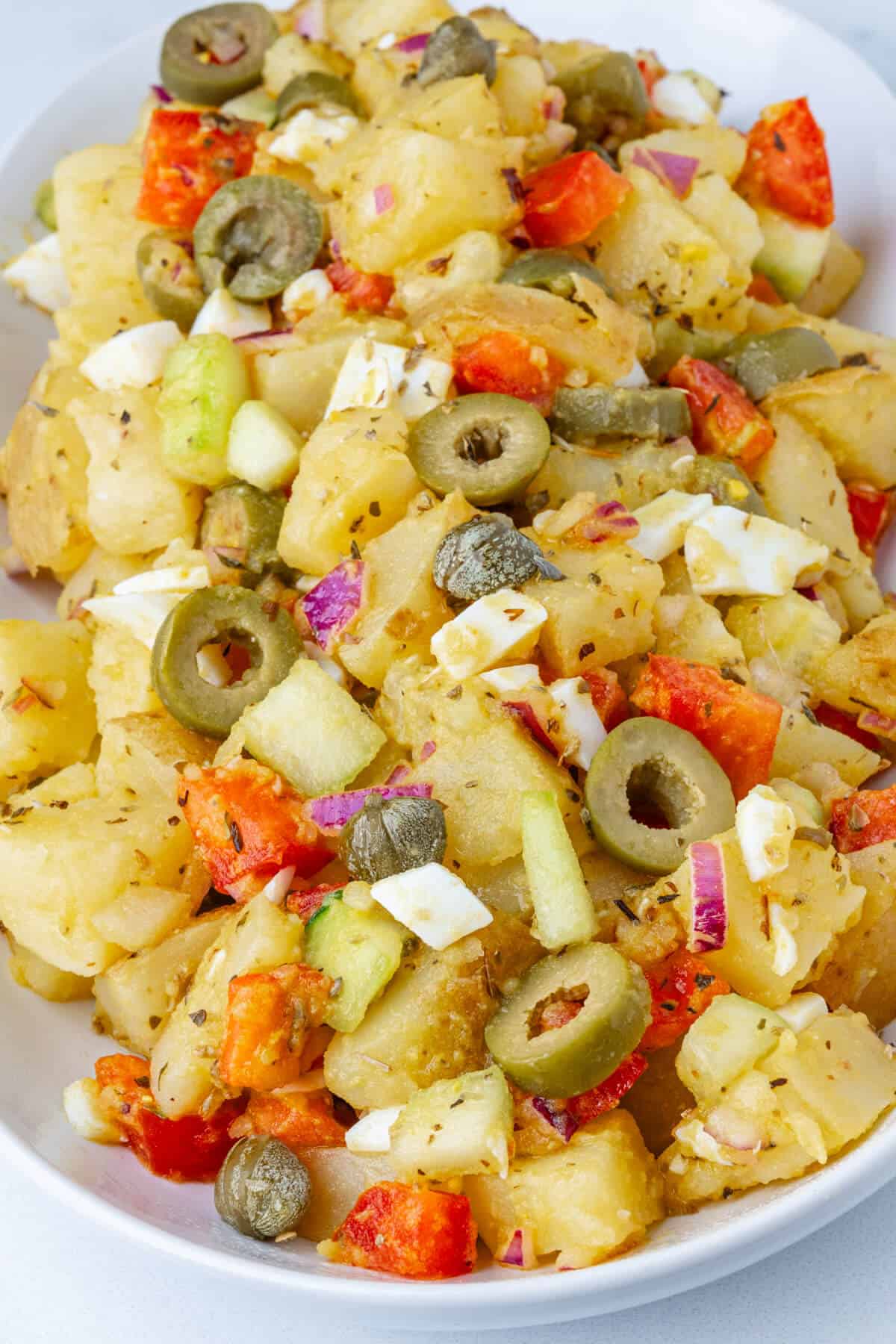 Salad with potatoes, olives, tomatoes, capers, onion, cucumber and egg