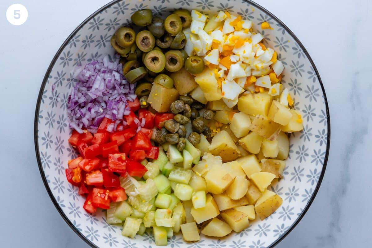 Potato salad ingredients chopped in a bowl before being mixed