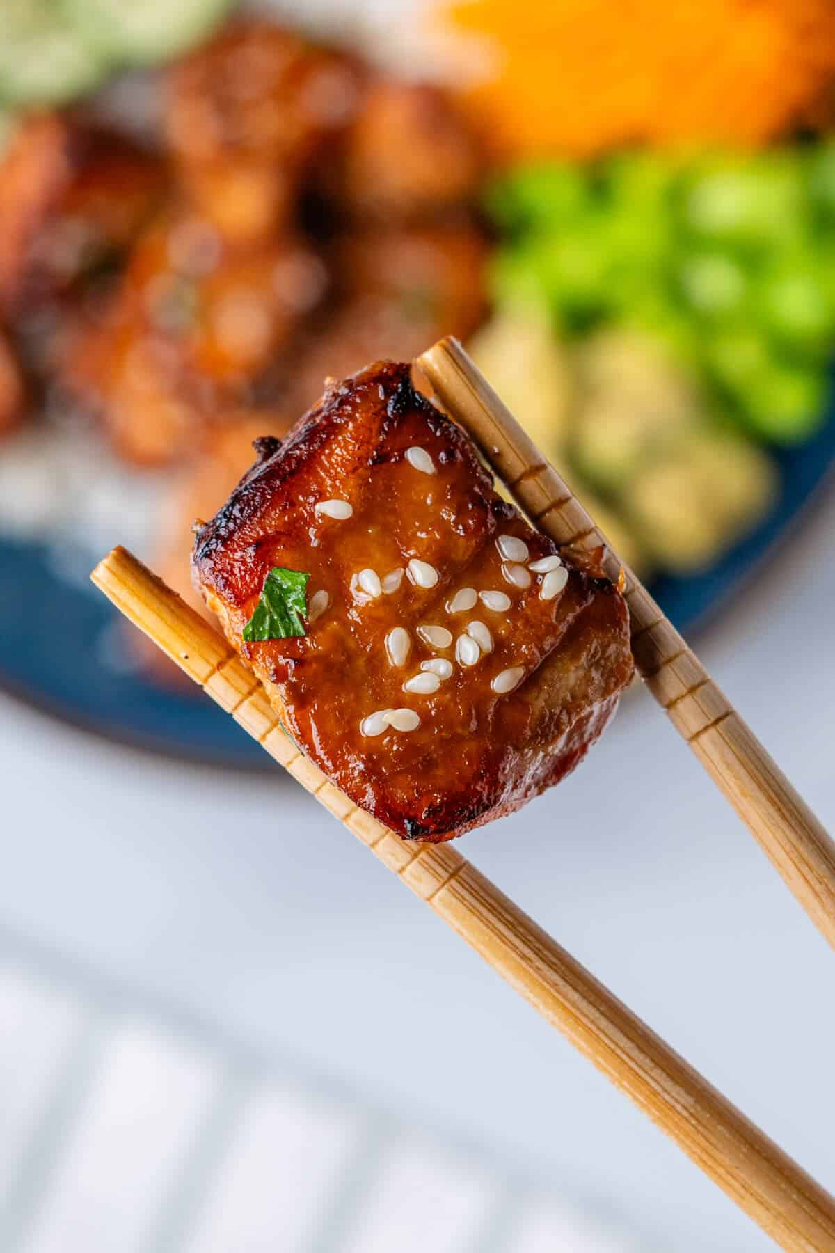 Close up of a piece of salmon held in chopsticks