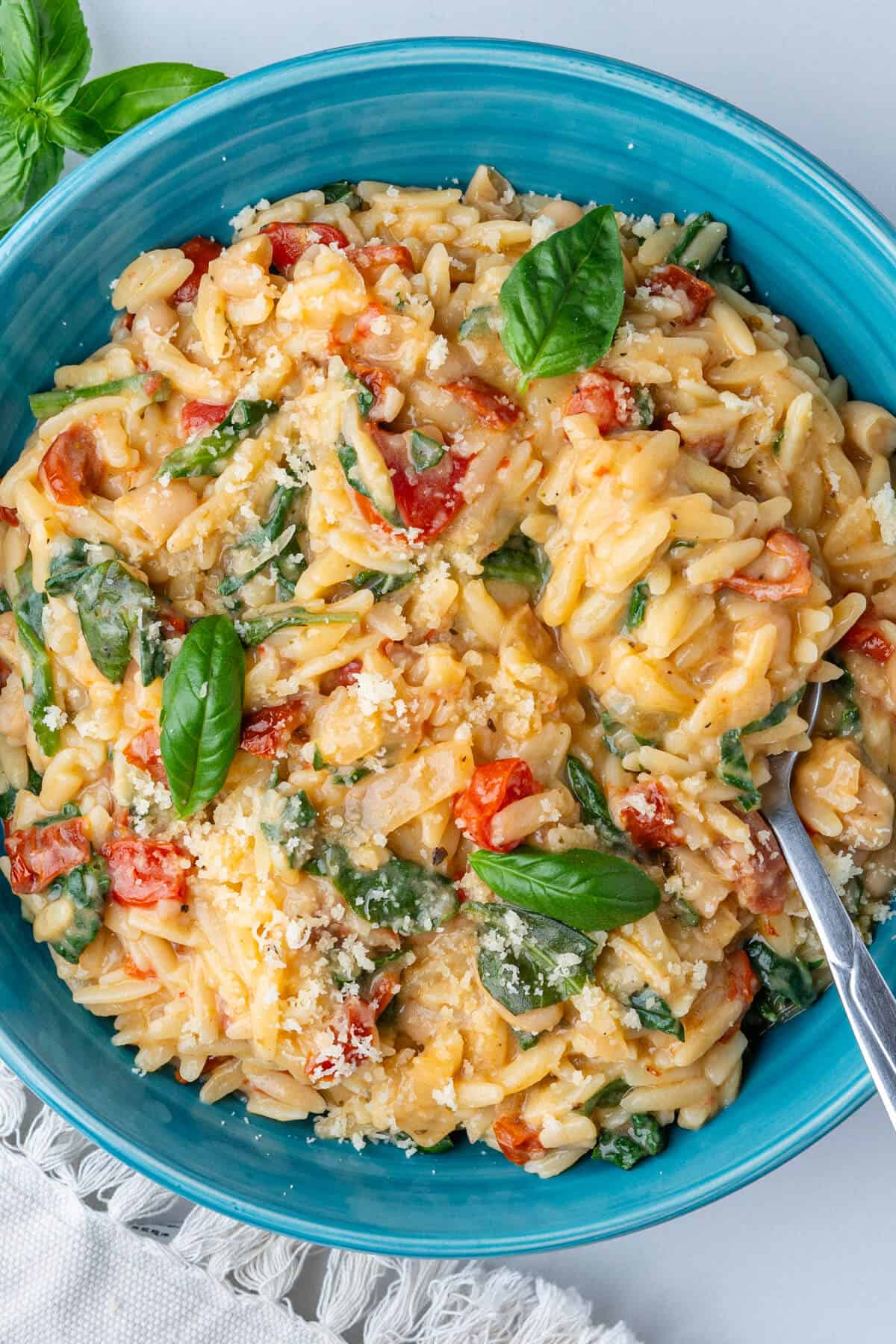 Creamy orzo pasta in a bowl with a spoon