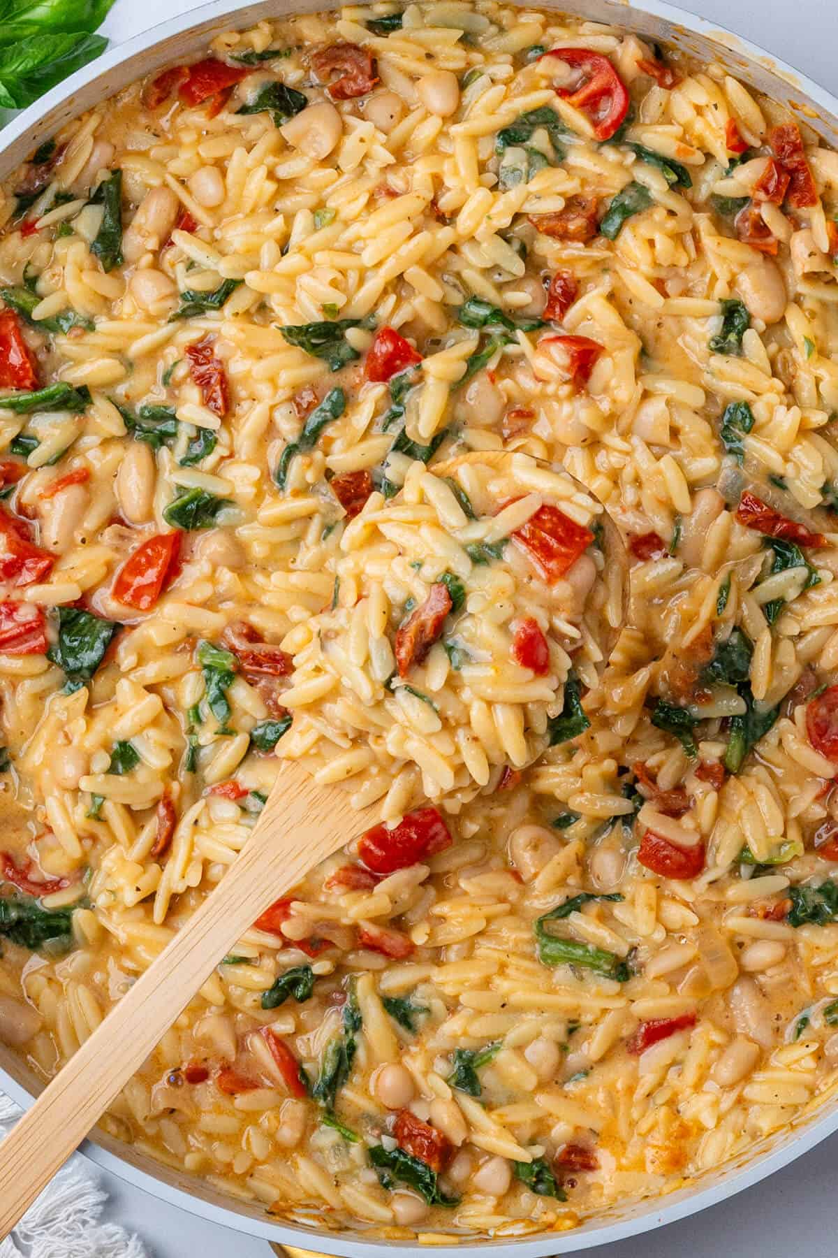 Wooden spoon coming out of a large pan of pasta