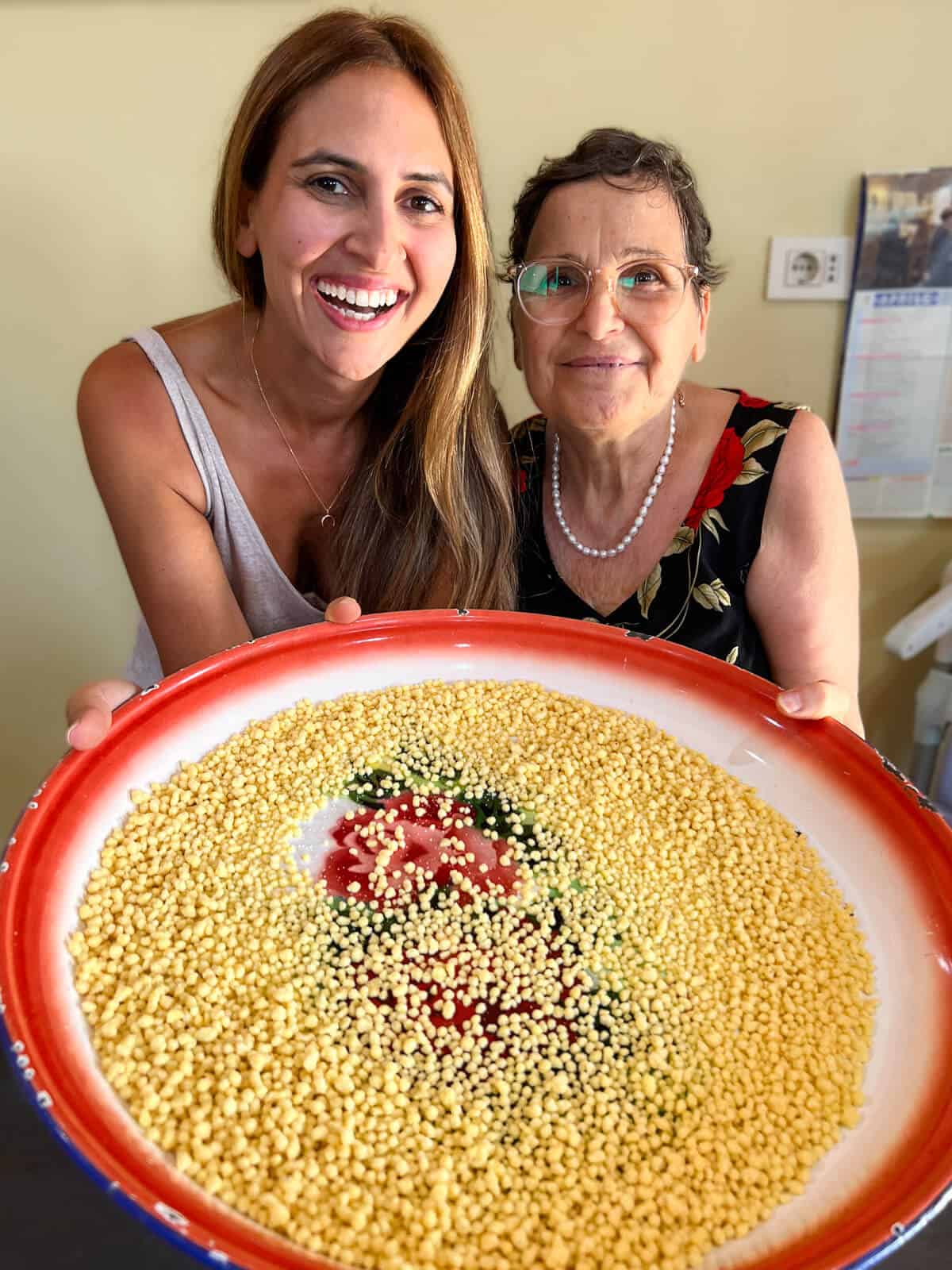 Ayeh and signora holding a large dish of fresh fregola