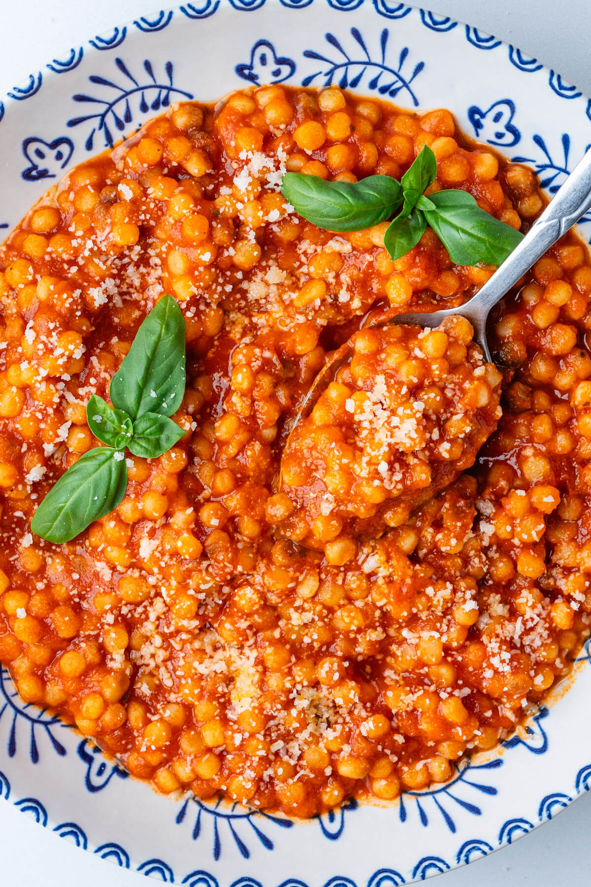 Spoon in a bowl of fregula pasta with sugo