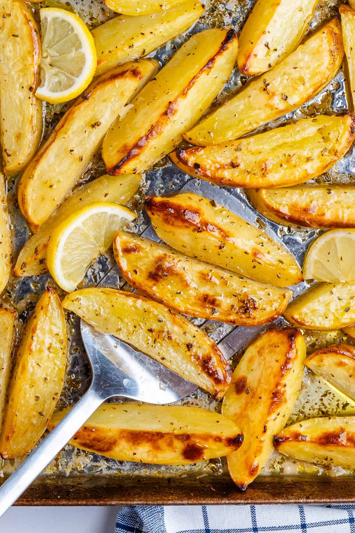 Spatula with Greek lemon potatoes on a baking tray