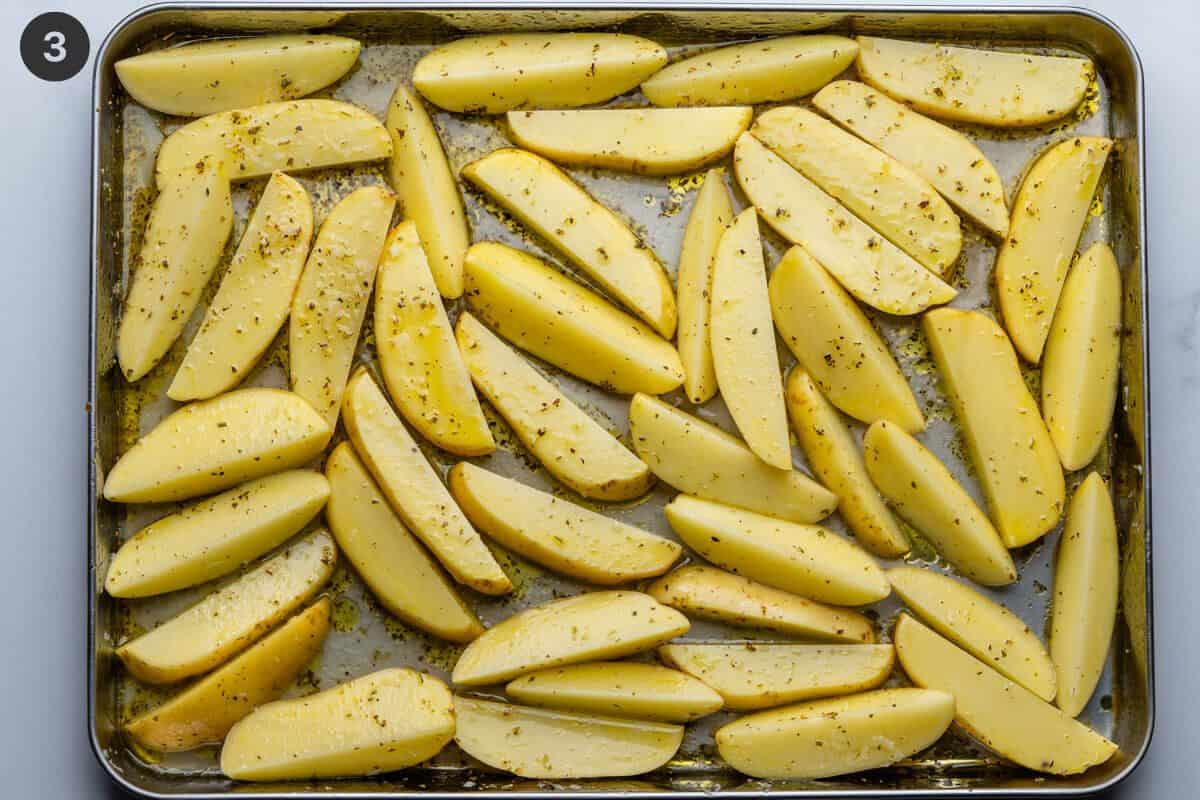 Potatoes mixed with dressing in a baking tray